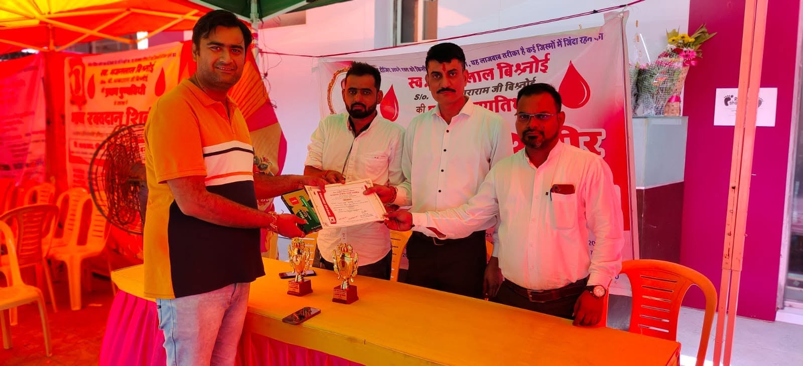 A blood donor receives a certificate and a token gift at the donation camp held under canopies outside the hospital.