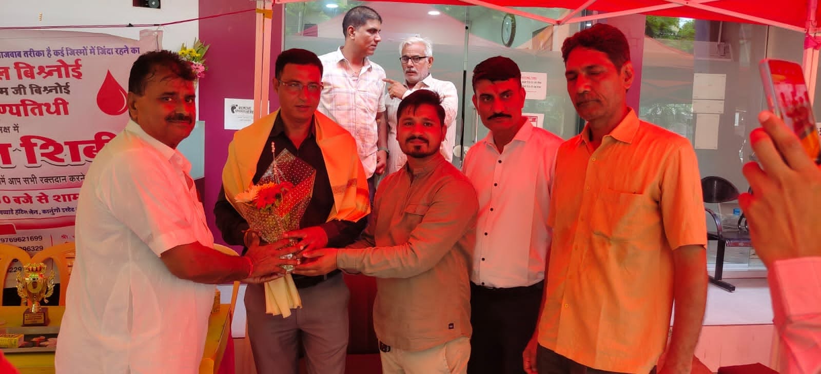 A guest is welcomed with a bouquet and a shawl at the blood donation camp.