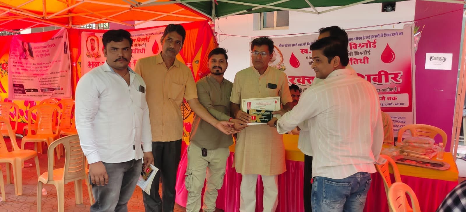 Organisers and donors gather around a certificate being presented at the blood donation camp.