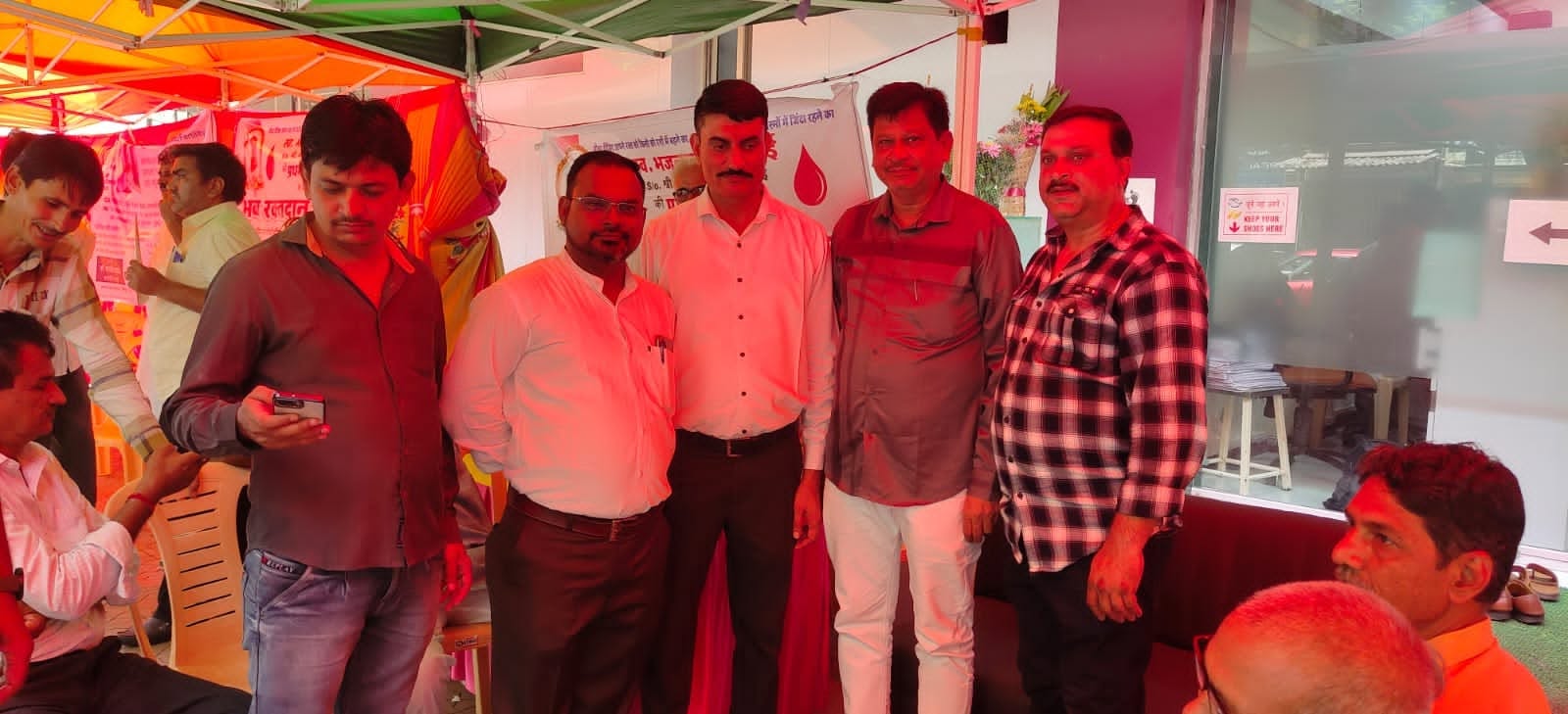 Volunteers and guests stand together at the blood donation camp beside the registration desk.