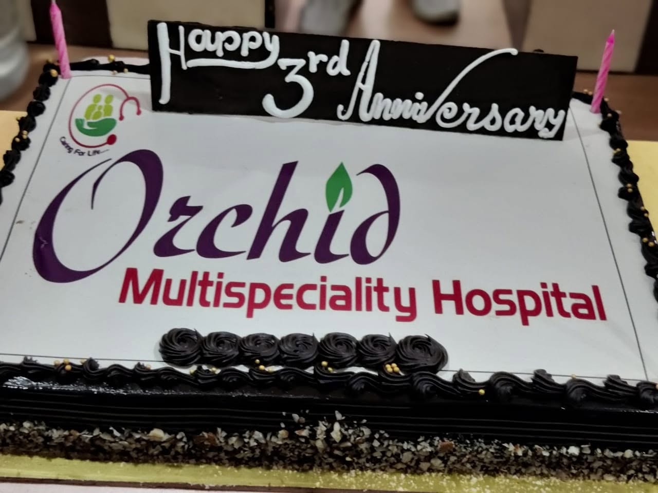 A cake iced with the Orchid Multispeciality Hospital logo and the words "Happy 3rd Anniversary".